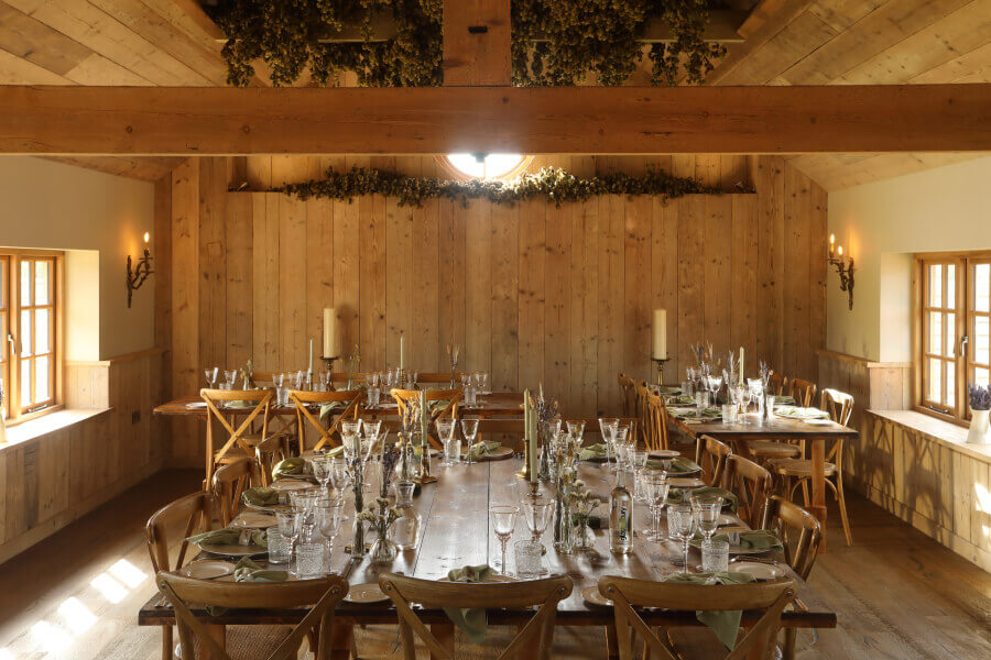 tables laid out with crockery, cutlery and glassware inside the feasting barn